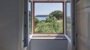 Ein Zimmer mit großem Fenster und Blick auf ein Gewässer und Grünflächen.