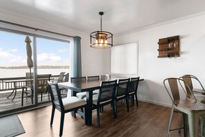 A dining area with a large table and chairs, a hanging light fixture, and a view through a glass door. - Lake front home on Klinger Lake in Sturgis,  Michigan (Sturgis)