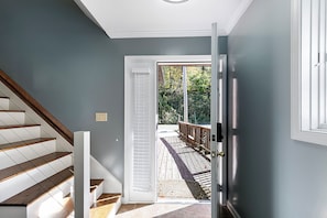 A staircase with wooden steps and white railings leading to a door with a view of a wooden deck and greenery outside. - Lake front home on Klinger Lake in Sturgis,  Michigan (Sturgis)