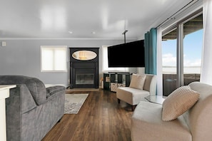A modern living room with a fireplace, a flat-screen TV, and a large window with curtains. - Lake front home on Klinger Lake in Sturgis,  Michigan (Sturgis)