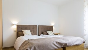 Un lit double avec un cadre en bois, deux tables de chevet et des lampes fixées au mur.