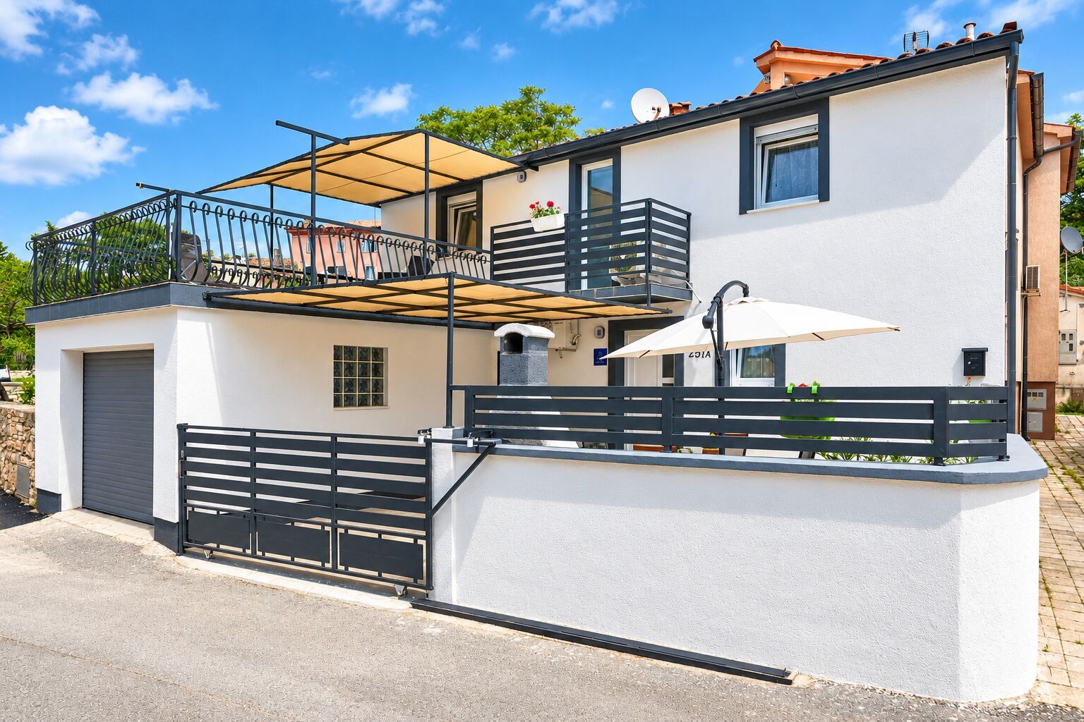 A two-story building with a balcony, a covered outdoor seating area, and a gated entrance.