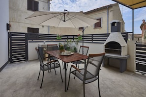 An outdoor patio with a table, chairs, an umbrella, and a pizza oven.