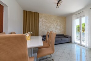 Et moderne spiseområde med et hvidt bord, brune stole og en sofa.