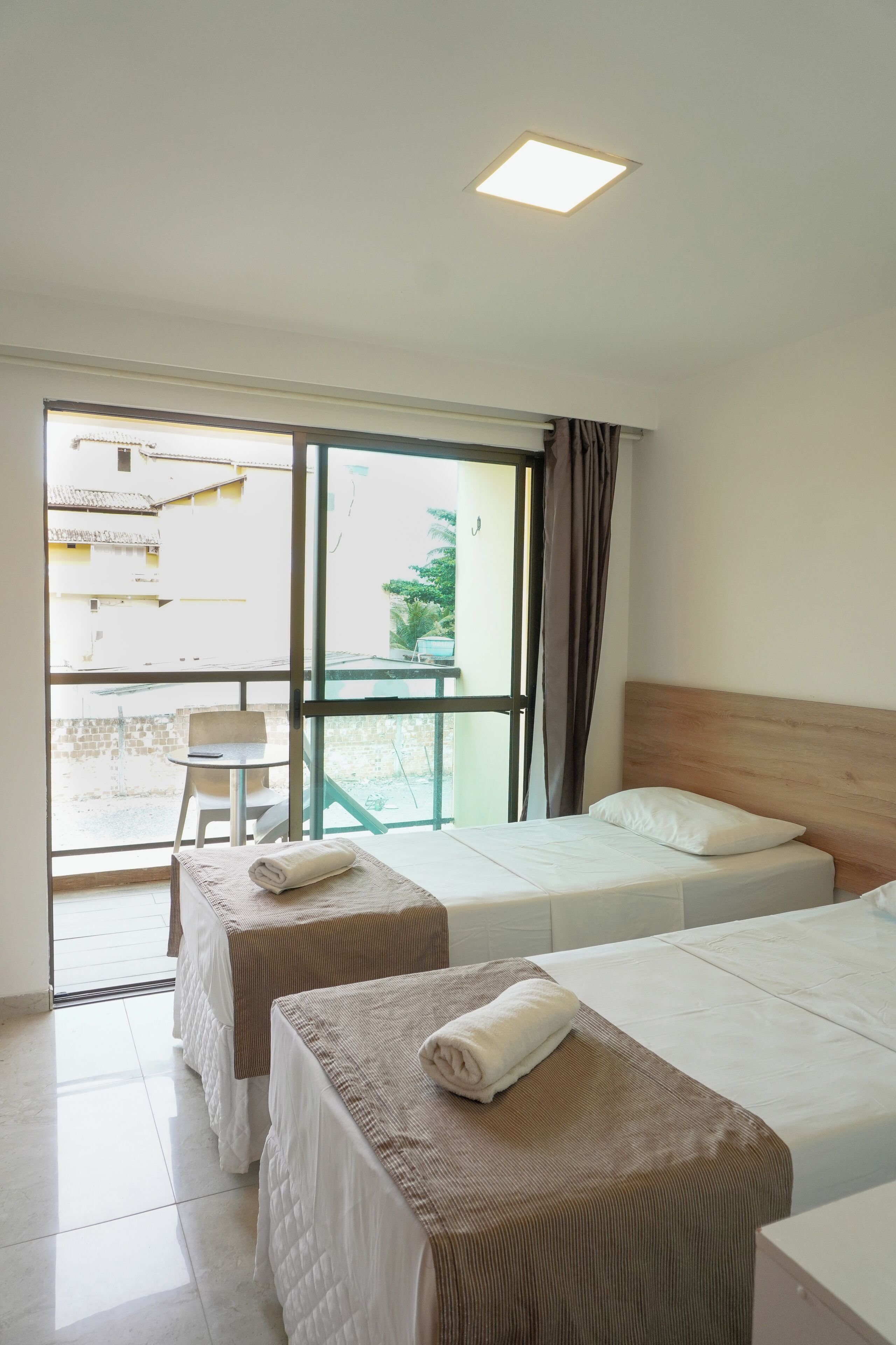 A hotel room with two beds, a small table, and a chair.