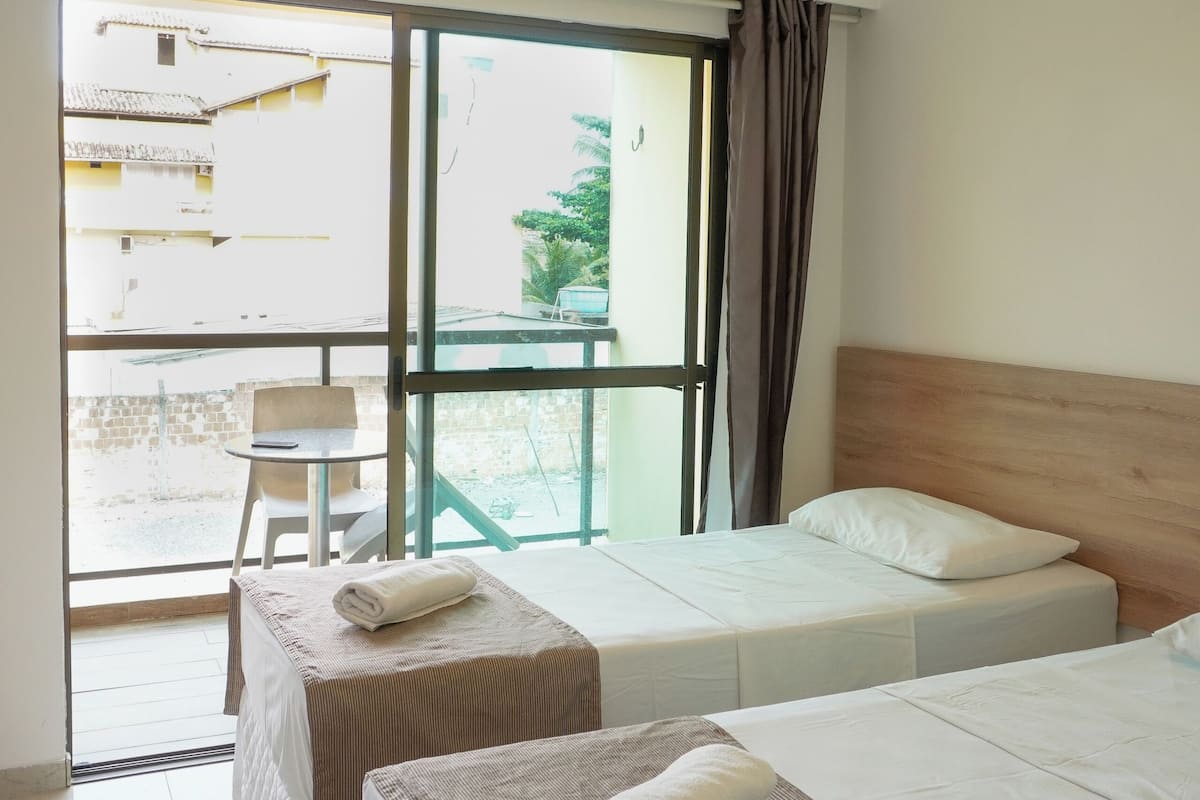 A hotel room with two beds, a small table, and a chair.