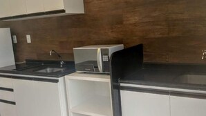 Une cuisine moderne avec des armoires blanches, un comptoir noir et un four à micro-ondes encastré.