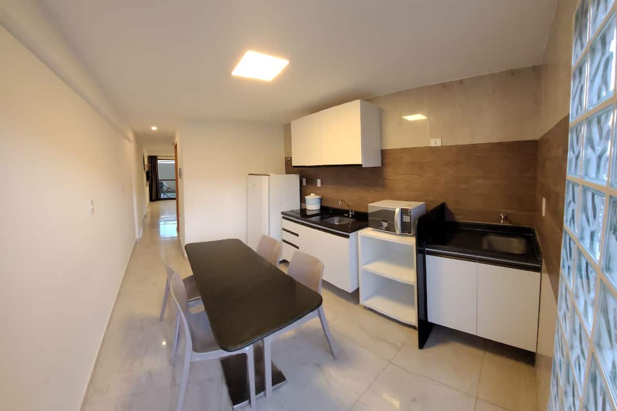 A modern kitchen with white cabinets, a black countertop, and a dining area with a table and chairs.