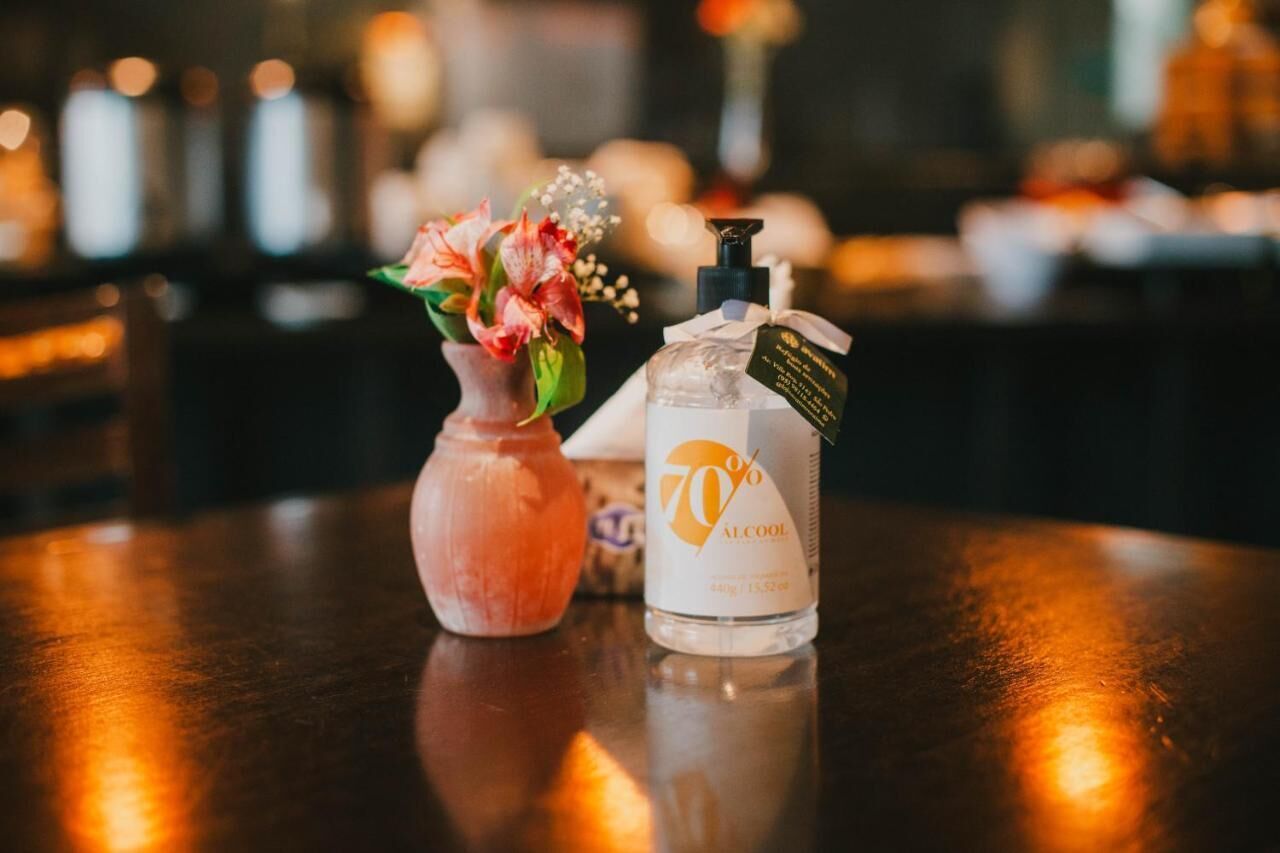 A bottle of 70% alcohol and a vase with flowers on a wooden table.