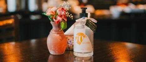 A bottle of 70% alcohol and a vase with flowers on a wooden table.