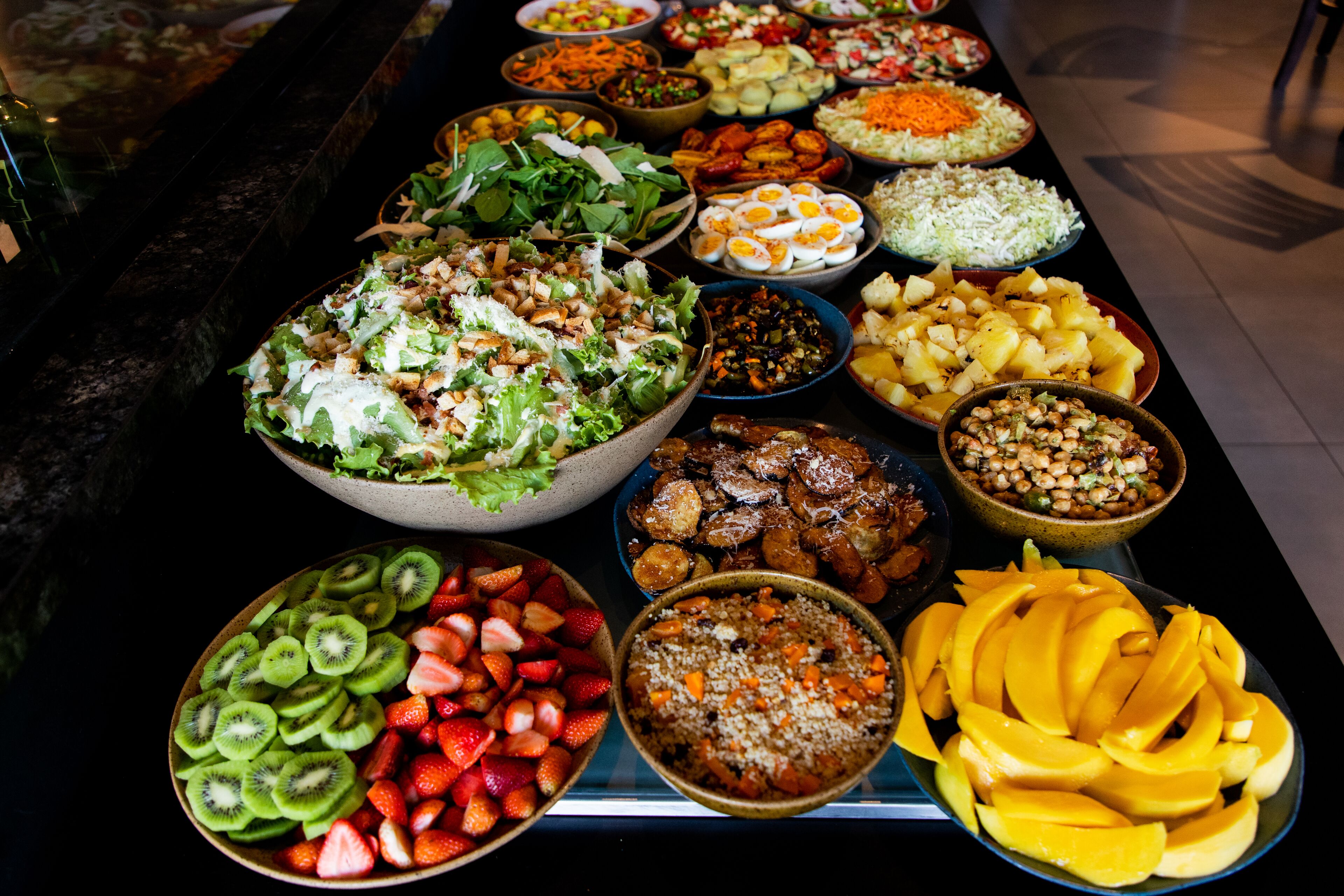 A buffet with various dishes including fruits, salads, and other food items.