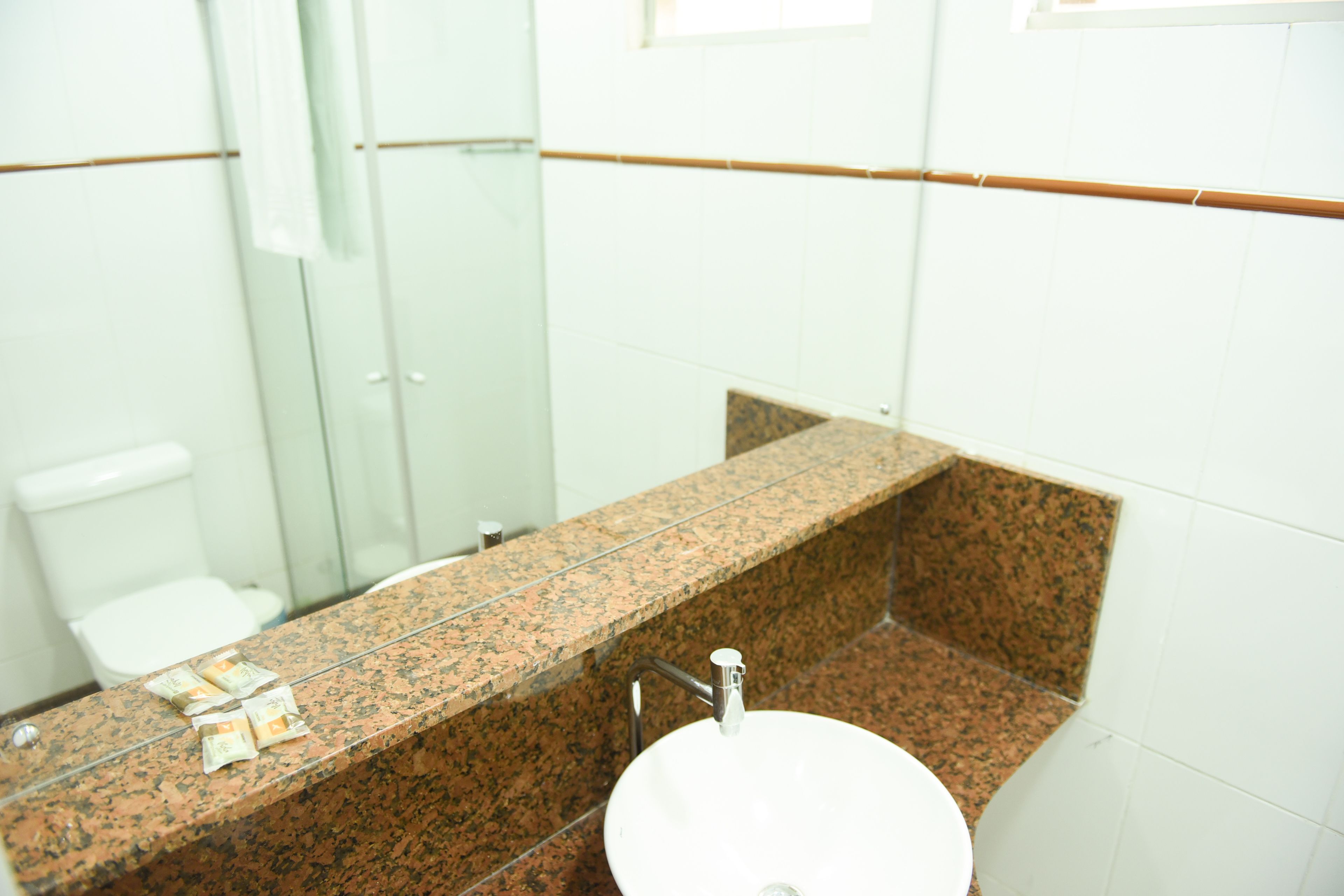 A bathroom with a granite countertop, a white sink, and a glass shower enclosure.