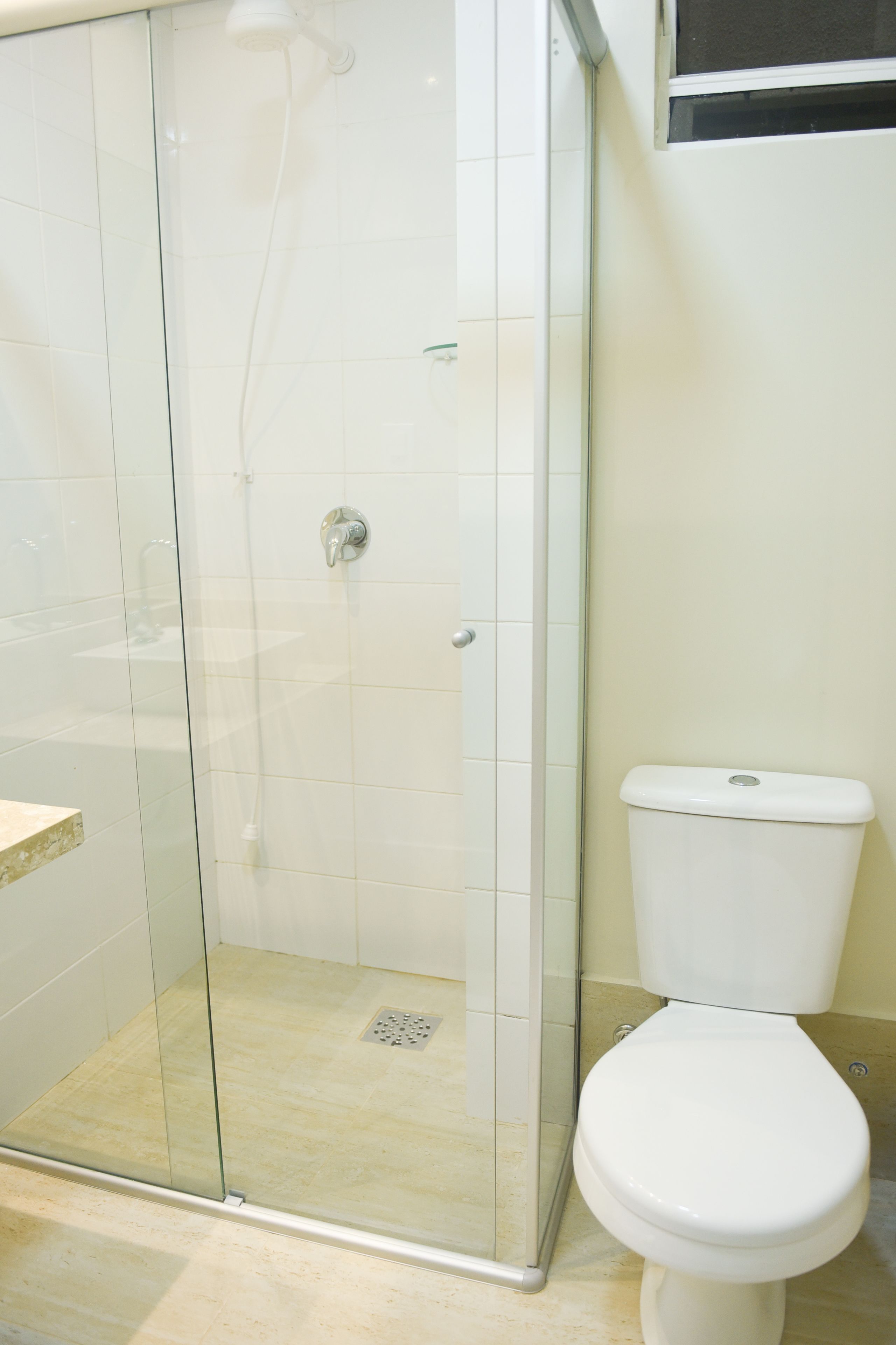 A bathroom with a glass-enclosed shower, a toilet, and a sink.