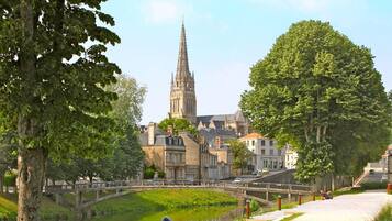A riverside pathway with a historic church and a bridge in the background.