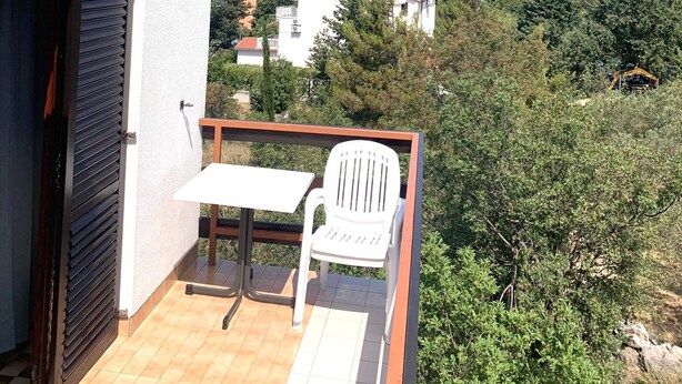 Un balcón con una mesa y una silla, con vista a un paisaje montañoso.