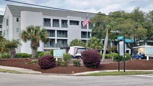 Un hotel de varios pisos con una bandera, palmeras y un carrito de golf.