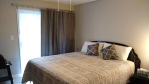 Habitación de hotel con una cama grande, una mesita de noche y una ventana con cortinas.
