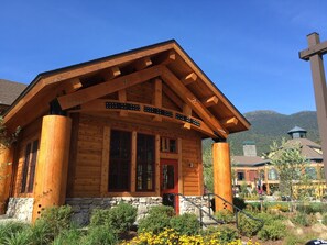 Un chalet en bois, doté de fondations en pierre, de grandes fenêtres et d’une porte rouge bien visible.