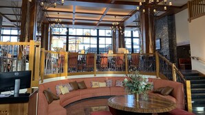 Eine großzügige Lobby mit einer gebogenen Couch, einem runden Holztisch und einer Treppe.