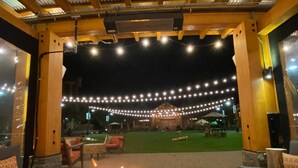 Ein Außenbereich mit Terrasse, Feuerstelle, Lichterketten und Sitzgelegenheiten.