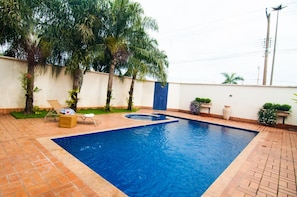 Une piscine rectangulaire aux parois bleues, entourée d’une terrasse carrelée.
