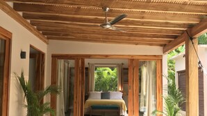 A spacious room with a wooden ceiling and a bed with a view of greenery outside.