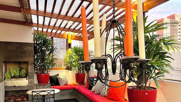 Un área de estar al aire libre acogedora con una chimenea, plantas en macetas y un candelabro moderno.