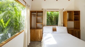 A bedroom with a bed, wooden shelving, and a window with curtains. - Tropical Boutique Sunset (Cóbano)