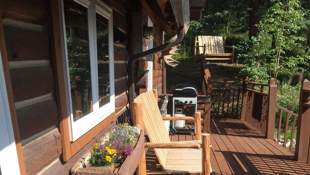 Eine Holzterrasse mit einer Bank und einem Tisch, umgeben von Blumenkästen.