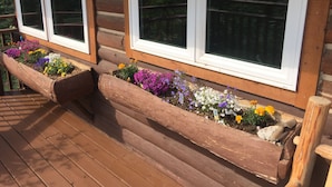 Eine Holzterrasse mit integrierten Pflanzkästen, die verschiedene Blumen enthalten.