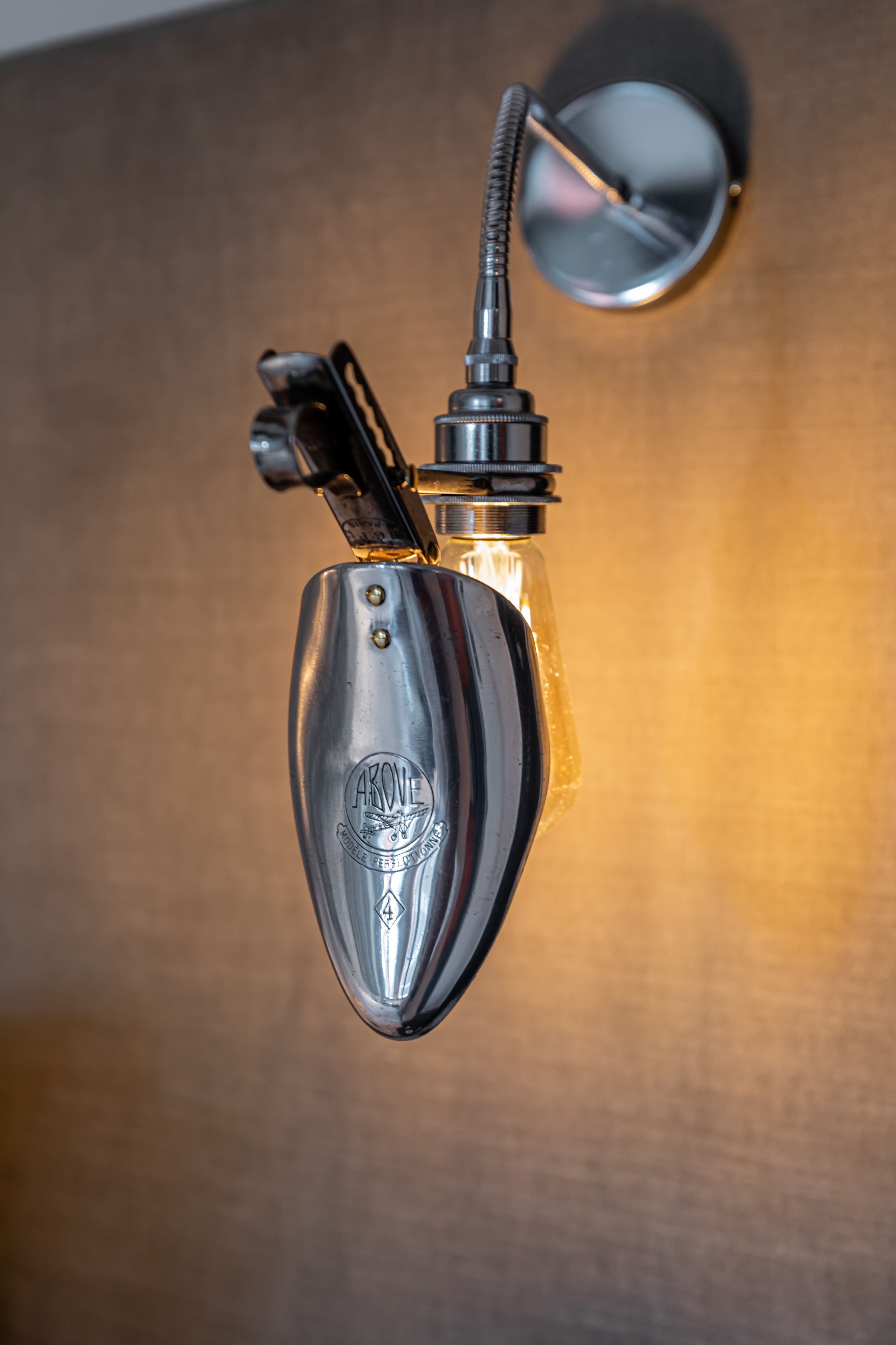 Una lámpara de pared con acabado metálico y bombilla de cristal transparente.