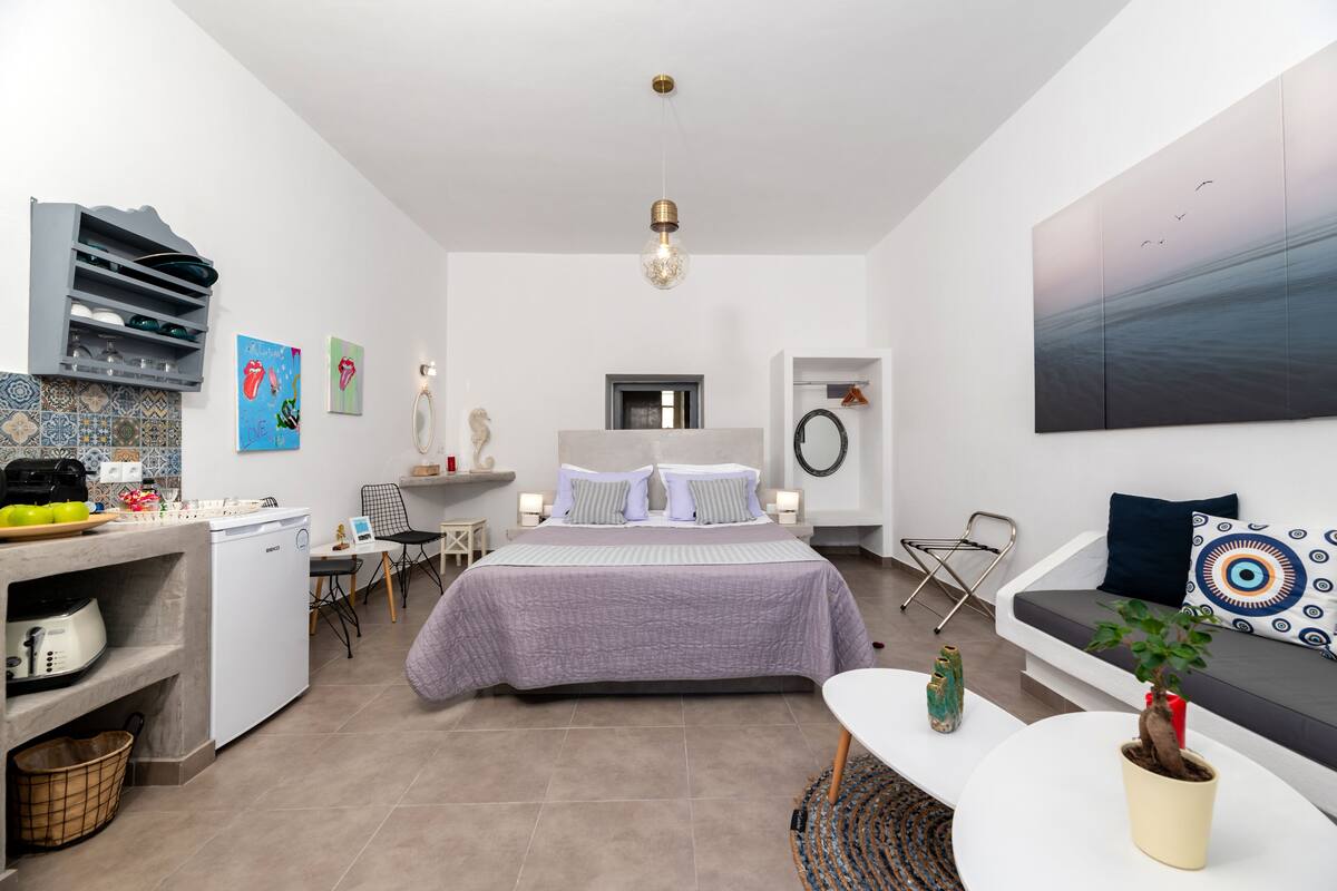 Ein kompakter, moderner Raum mit Bett, Küchenzeile und Sitzecke.