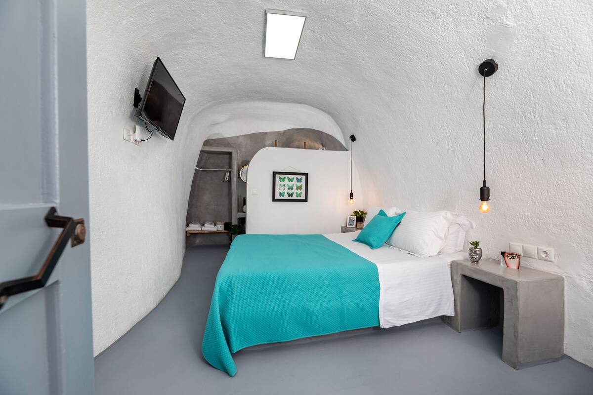 Ein gemütliches Schlafzimmer mit Bett, Nachttisch, Wand-Fernseher und einem gerahmten Bild.
