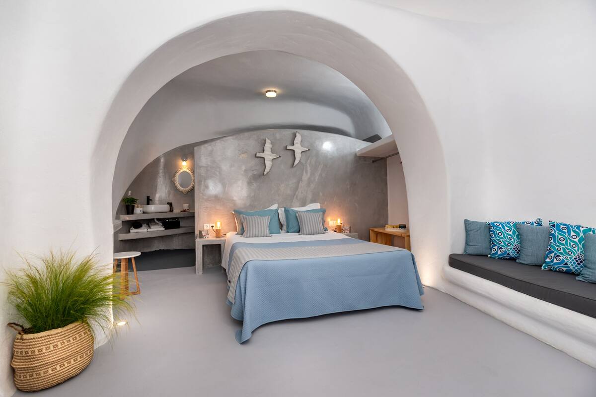 Ein modernes Schlafzimmer mit Bett, einer Sitzecke und einer Küche im Hintergrund.