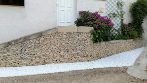 Un edificio con una puerta blanca, una ventana pequeña y un camino de piedra que conduce a la entrada.