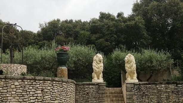 Un muro de piedra con dos estatuas de leones y una escalera de piedra que sube a una puerta.