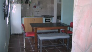 Cocina compacta con refrigerador, microondas y una pequeña mesa de comedor con dos sillas.
