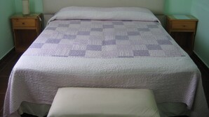 Una cama con colcha, dos mesitas de noche y una lámpara de noche.
