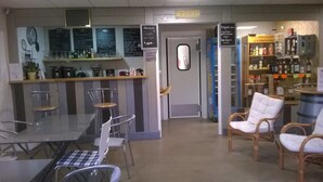Un café doté d’un bar, d’un espace pour s’asseoir et d’un présentoir où sont exposées les boissons.