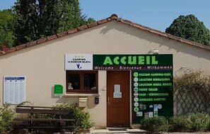 A small building with a green signboard listing amenities like camping cars, bungalows, and mobile homes. - Camping l'Agrion Bleu - Bungalow (Saint-Martial-de-Valette)