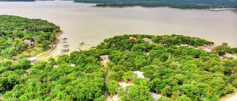 Vista aérea de una zona costera con abundante vegetación, un puerto deportivo con barcos y edificios residenciales.