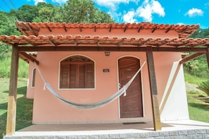 A small building with a tiled roof, two wooden doors, and a hammock tied between two wooden posts.