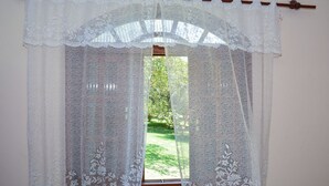 A window with a white lace curtain and a wooden frame. - Pousada Vale dos Sonhos (Saquarema)