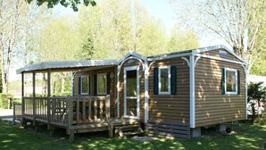 Eine Holzhütte mit Veranda und überdachter Terrasse, umgeben von Bäumen.