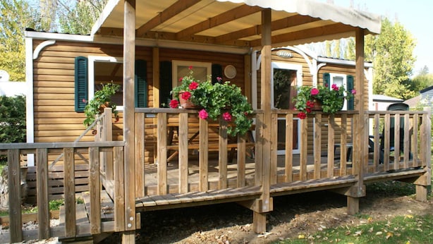 Eine Holzhütte mit einer überdachten Veranda, einer Holzterrasse und Pflanzkübeln.