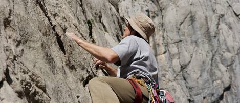 A person climbing a rocky cliff with climbing gear.