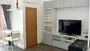 Ein kompakter Wohnbereich mit Fernseher, Schreibtisch und Stuhl.