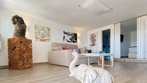 Ein modernes Wohnzimmer mit Holzboden, einem weißen Sofa, einem Couchtisch und einer dekorativen Elefantenskulptur.
