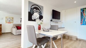 Ein moderner Essbereich mit einem weißen Tisch und Stühlen, einer Blumenvase und Kunstwerken an den Wänden.