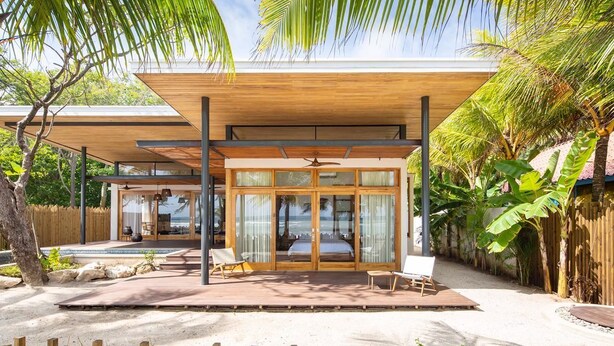 Une villa moderne dotée d’un patio couvert, de grandes portes vitrées et d’un espace piscine.